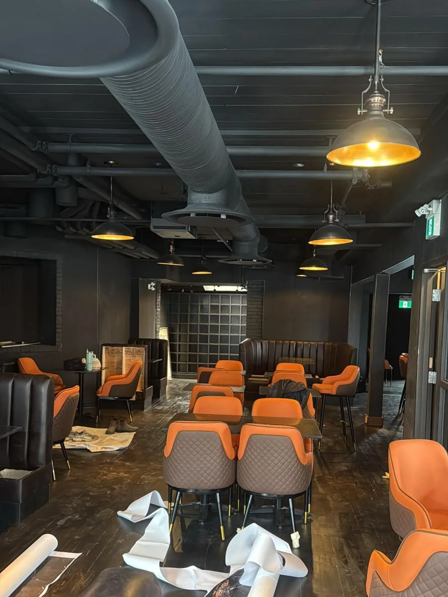 Restaurant interior with ceiling, exposed ductwork, pipes and walls painted matte black